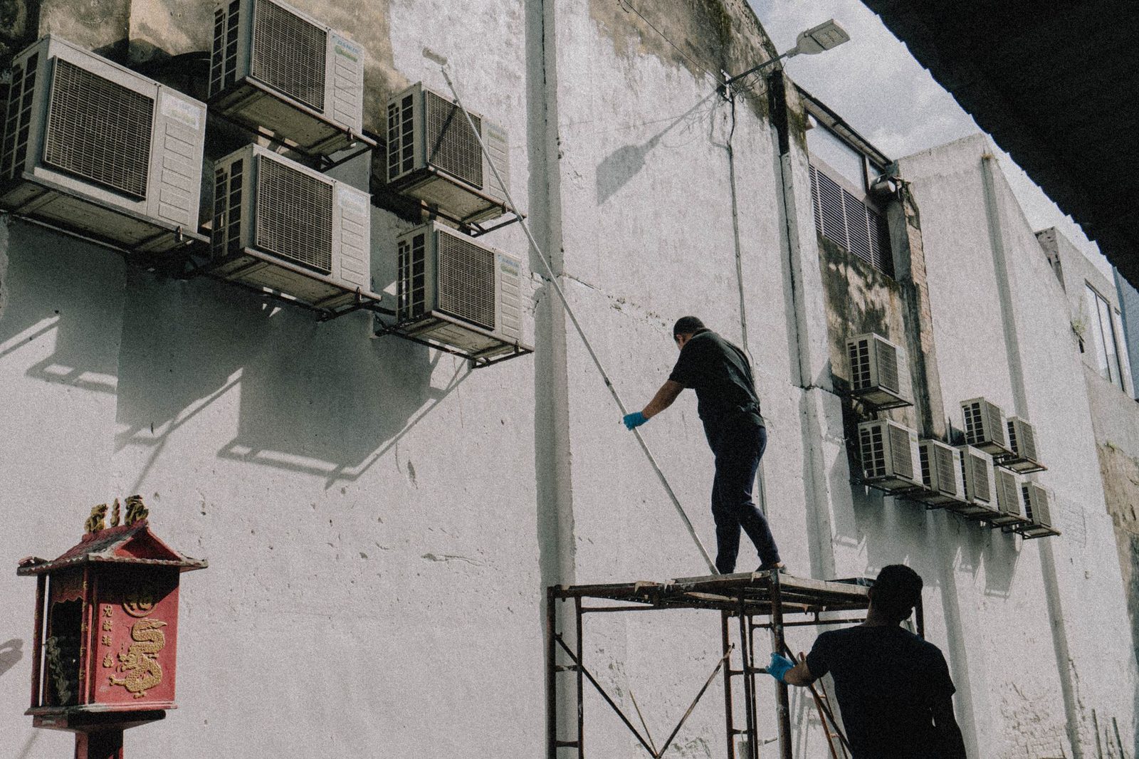 Workers pressure washing a building exterior wall